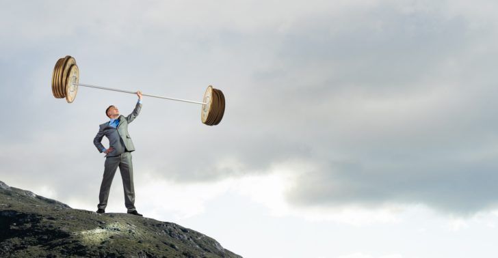 西裝男子在山頂單手舉起巨大金幣槓鈴，象徵財務槓桿的力量